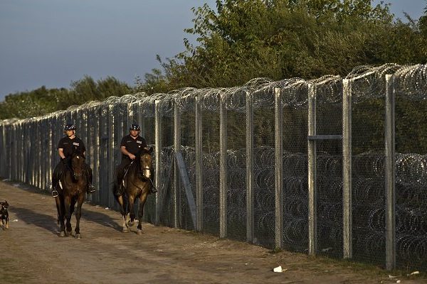 Hungarian police on horses patrol near the fence after the border between Serbia and Hungary was closed, in Roszke, southern Hungary, Monday, Sept. 14, 2015. Hungary is set to introduce much harsher border controls at midnight  laws that would send smugglers to prison and deport migrants who cut under Hungary's new razor-wire border fence. The country's leader was emphatically clear that they were designed to keep the migrants out. (AP Photo/Muhammed Muheisen)